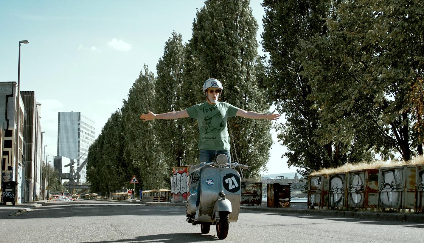 man standing on a vespa